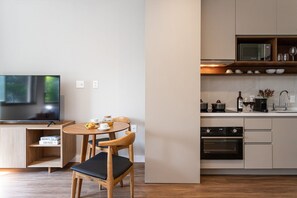 A modern kitchen with a dining area, a flat-screen TV, and a microwave. - Apartamentos mobiliados com excelente vista e localização - Higienópolis (São Paulo)