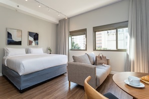 Une chambre d’hôtel avec un lit, un canapé, une table à manger et deux fenêtres.