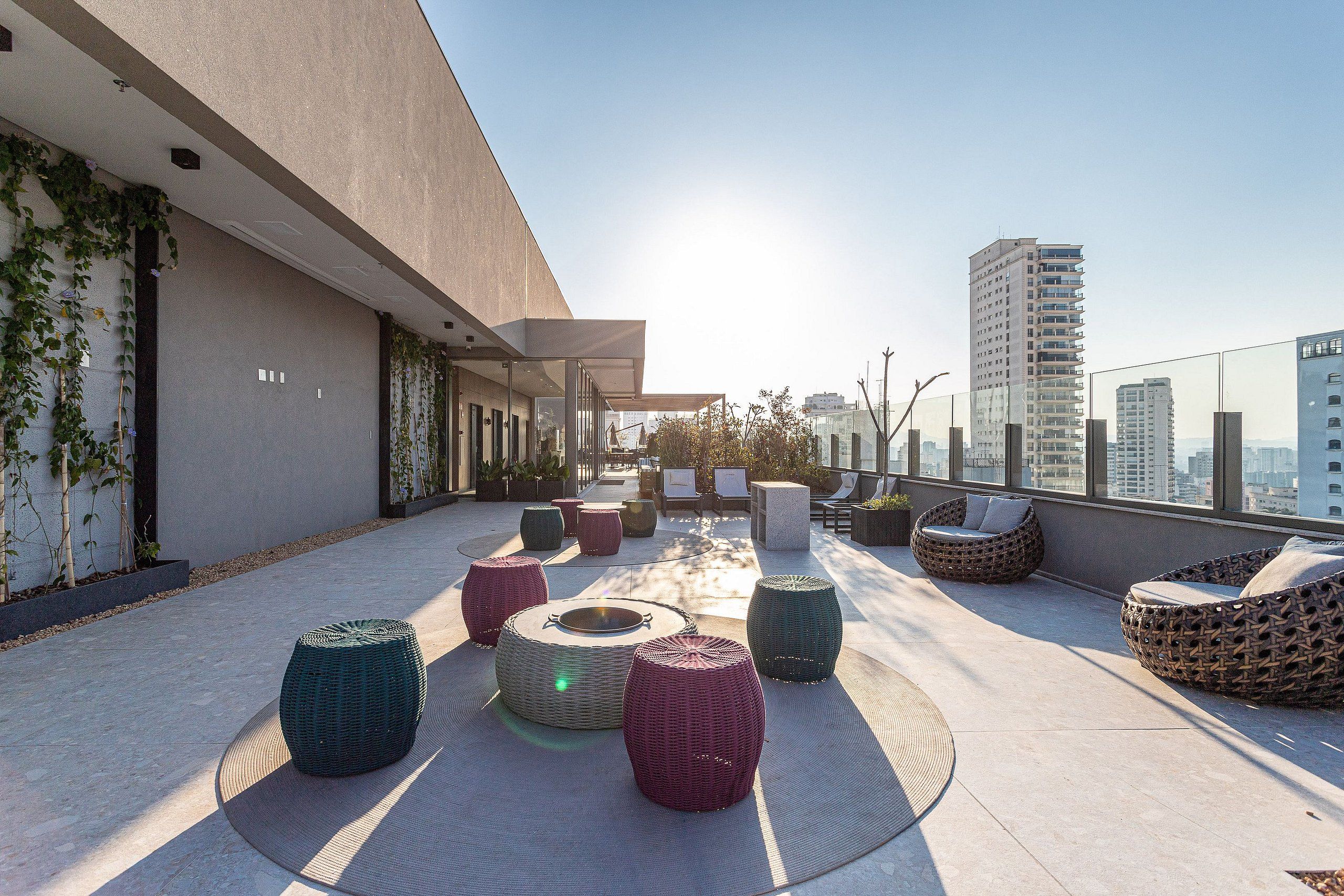 A rooftop terrace with outdoor seating, a view of the city, and a modern building facade.