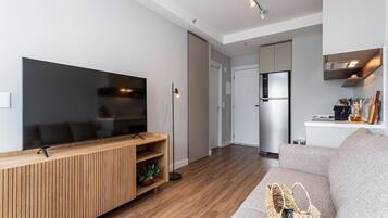 A modern living room with a flat-screen TV, wooden entertainment unit, and a grey sofa.