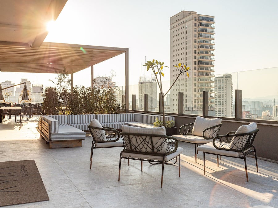 Una terraza en la azotea con mobiliario, una pérgola y vistas a la ciudad.