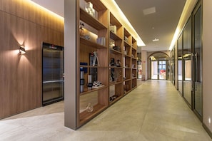 Un couloir moderne avec un mur en bois, une bibliothèque intégrée et un ascenseur visible.