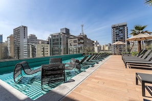 A rooftop pool area with lounge chairs and a wooden deck. - Apartamentos mobiliados com excelente vista e localização - Higienópolis (São Paulo)