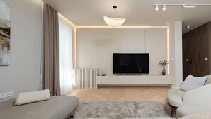 Een moderne woonkamer met een flatscreen televisie, een bank, een salontafel en een decoratieve vaas.