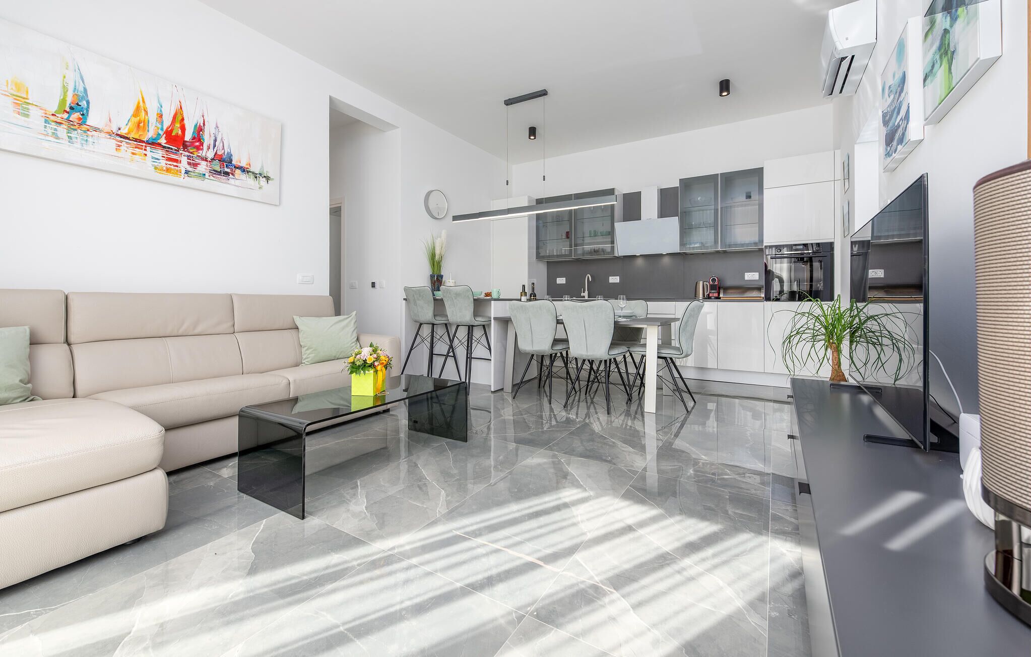 A modern living room with a sofa, coffee table, and a dining area with chairs and a table.