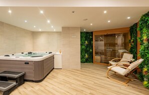 A modern spa room with a hot tub, wooden flooring, a glass shower enclosure, and a seating area with a chair. - Luxurious home in Vrsi with sauna (Vrsi)