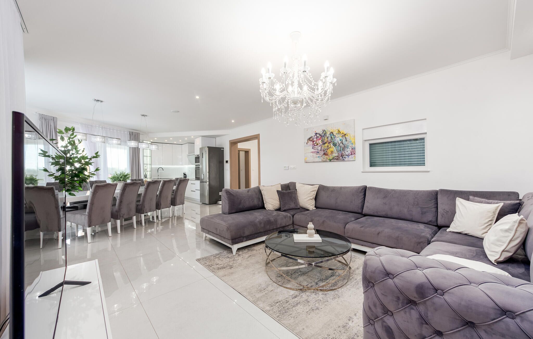Una sala moderna con un sofá modular, una mesa de centro de vidrio y una araña.