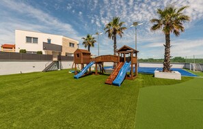 A playground with slides and a climbing structure, surrounded by artificial grass and palm trees. - Luxurious home in Vrsi with sauna (Vrsi)