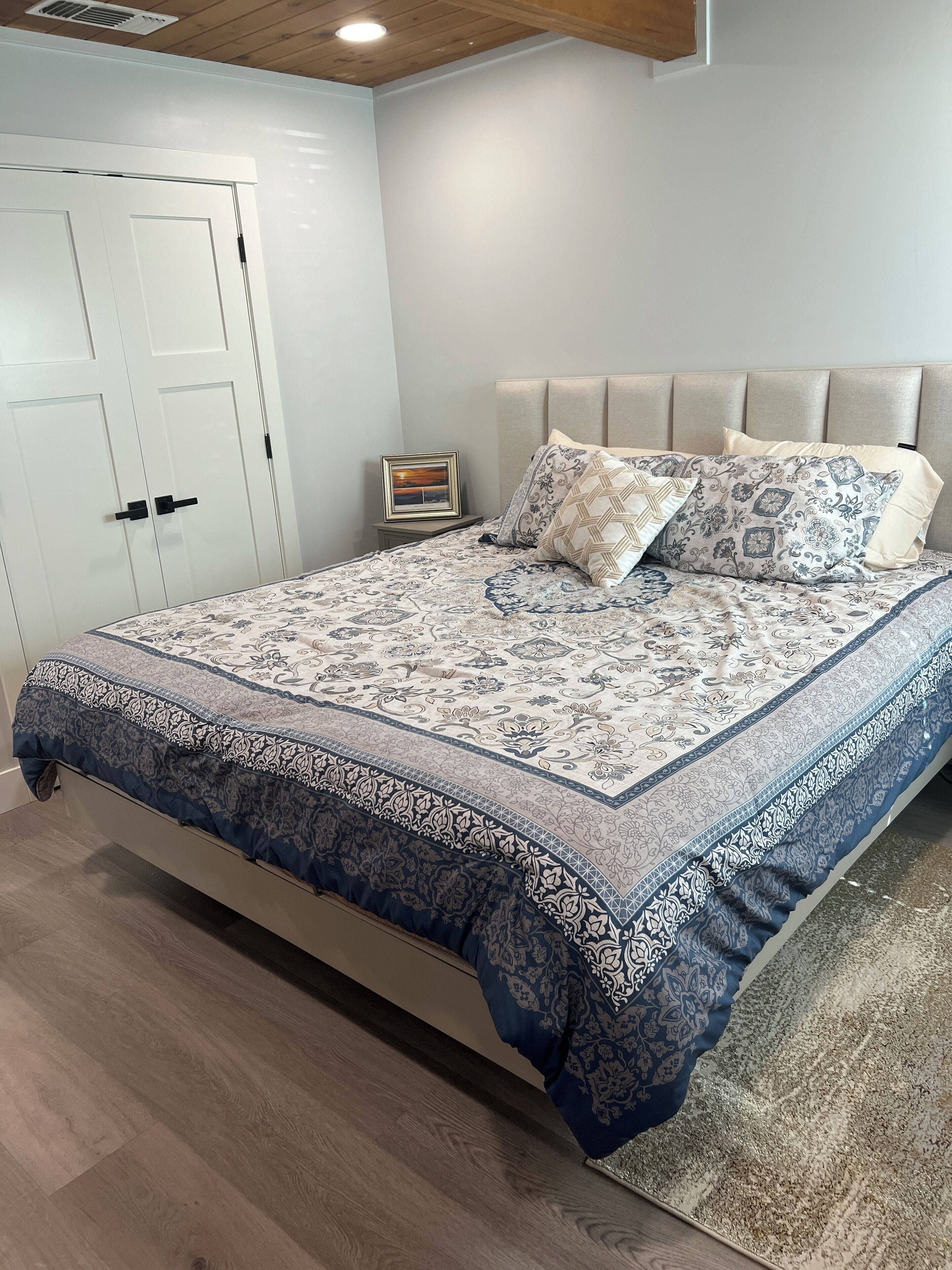 Una camera da letto con un letto, un comodino, un quadro incorniciato e un armadio.