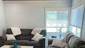 A living room with a grey sofa, a coffee table, and a side table with a plant.