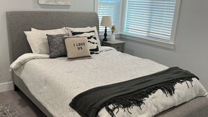 A bedroom with a bed, a nightstand, a lamp, and a window with blinds.
