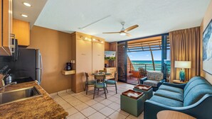 A modern hotel room with a kitchenette, a dining area, a seating area with a view of the ocean, and a balcony with a pool. - Kuleana Club - 611 (Lahaina)