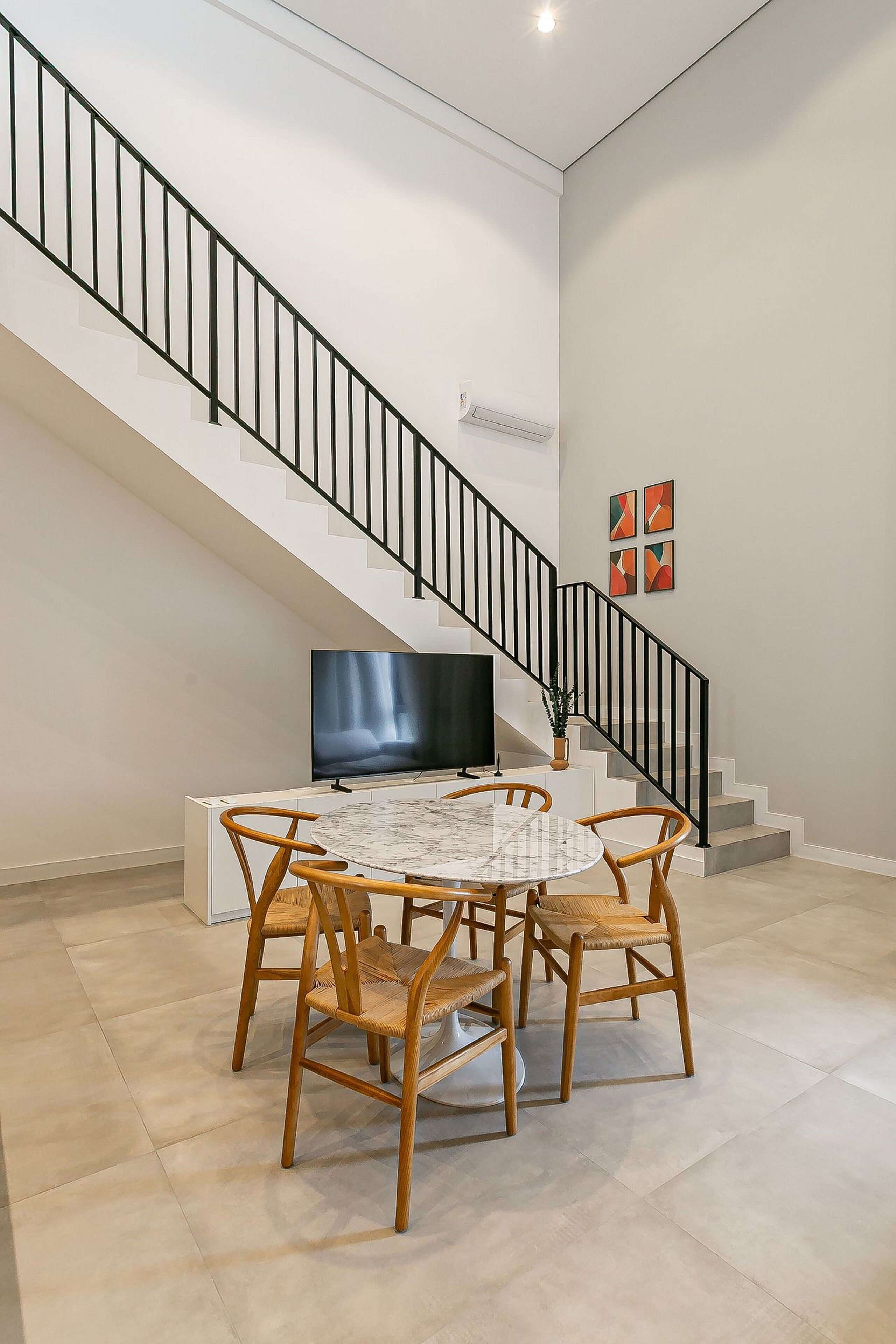Un espace repas comprenant une table, des chaises, un téléviseur et un escalier.