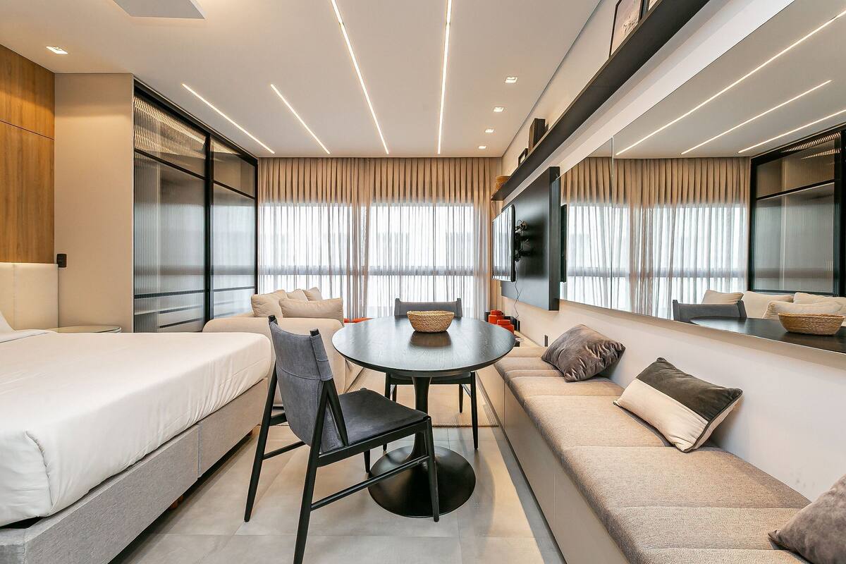 Une chambre d’hôtel moderne équipée d’un lit, d’un canapé, d’une table à manger et d’une grande fenêtre avec des rideaux.