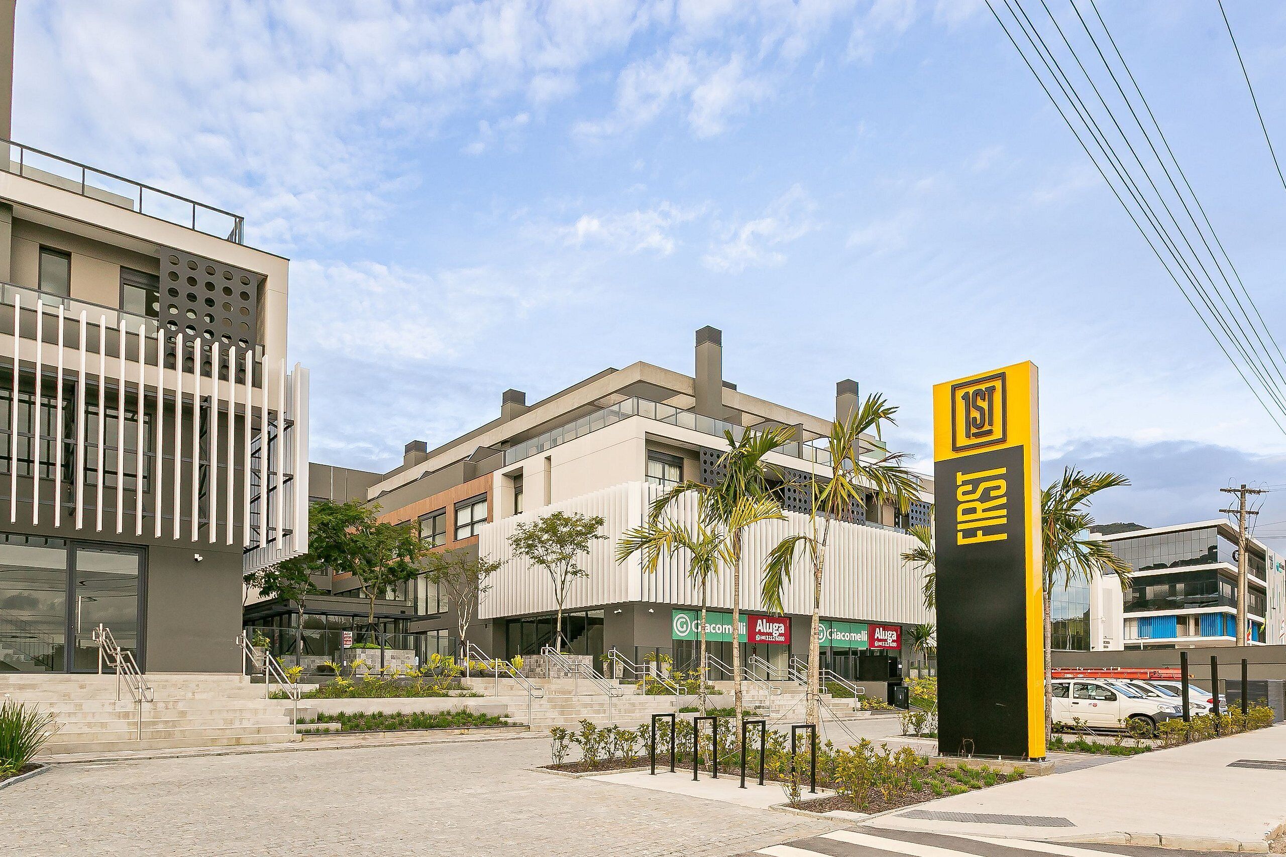 Un edificio moderno con un letrero destacado que dice '1st', una escalera y un área de estacionamiento.