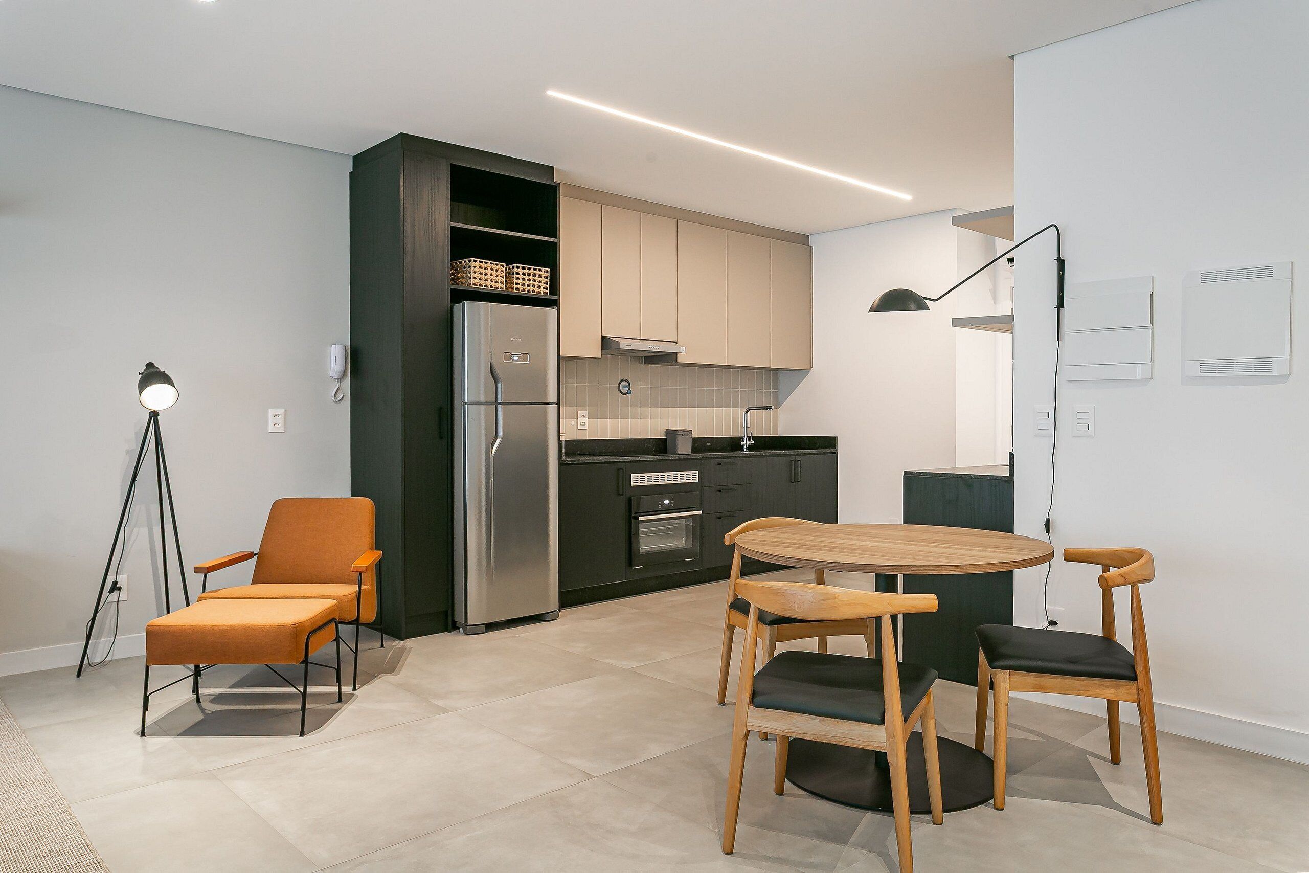 A modern kitchen with a refrigerator, oven, and dining area with chairs and a table.