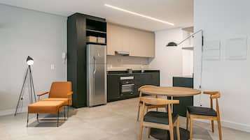 A modern kitchen with a refrigerator, oven, and dining area with chairs and a table.