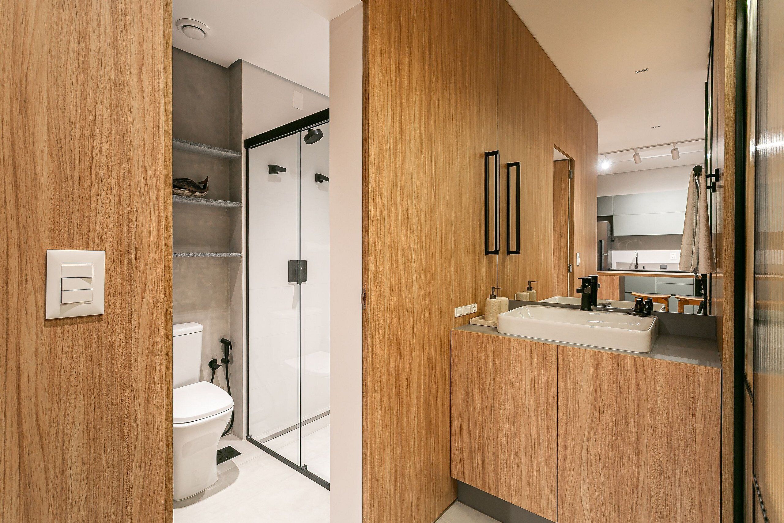 Un baño moderno con tocador de madera, inodoro y cabina de ducha de vidrio.