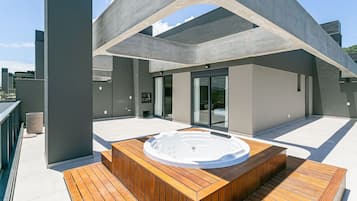 Une terrasse sur le toit dotée d’un jacuzzi, d’une plateforme en bois et d’une architecture moderne.