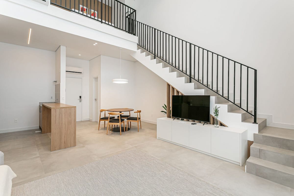 Un intérieur moderne comprenant un escalier, un coin repas et une cuisine.