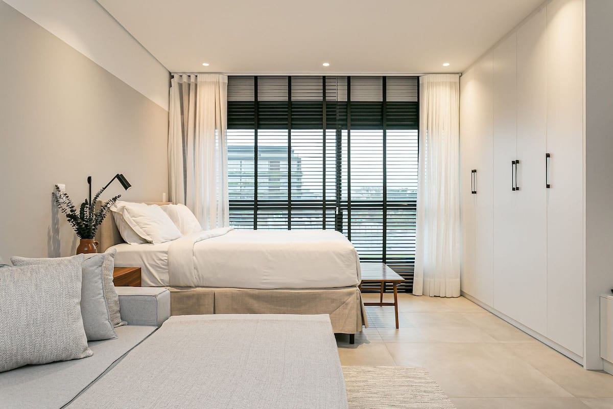 Une chambre moderne avec un lit, des tables de chevet, un canapé et une armoire.