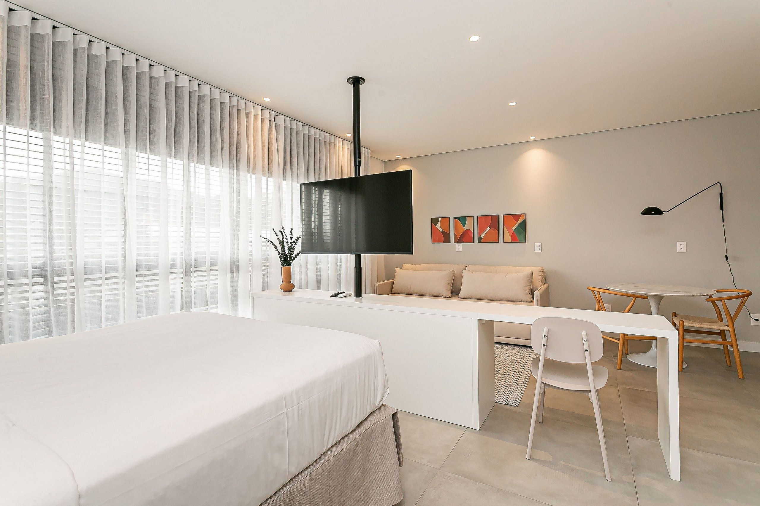 Una habitación de hotel moderna con una cama, un escritorio, un sofá y un televisor.