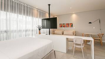 Una habitación de hotel moderna con una cama, un escritorio, un sofá y un televisor.