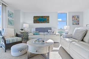 A modern living room with a sofa, armchair, coffee table, and decorative pillows. - Sunset Bay Views! 3 bed, 2 bath End Unit Condo with Pool, Dock and Water Access (Pensacola Beach)