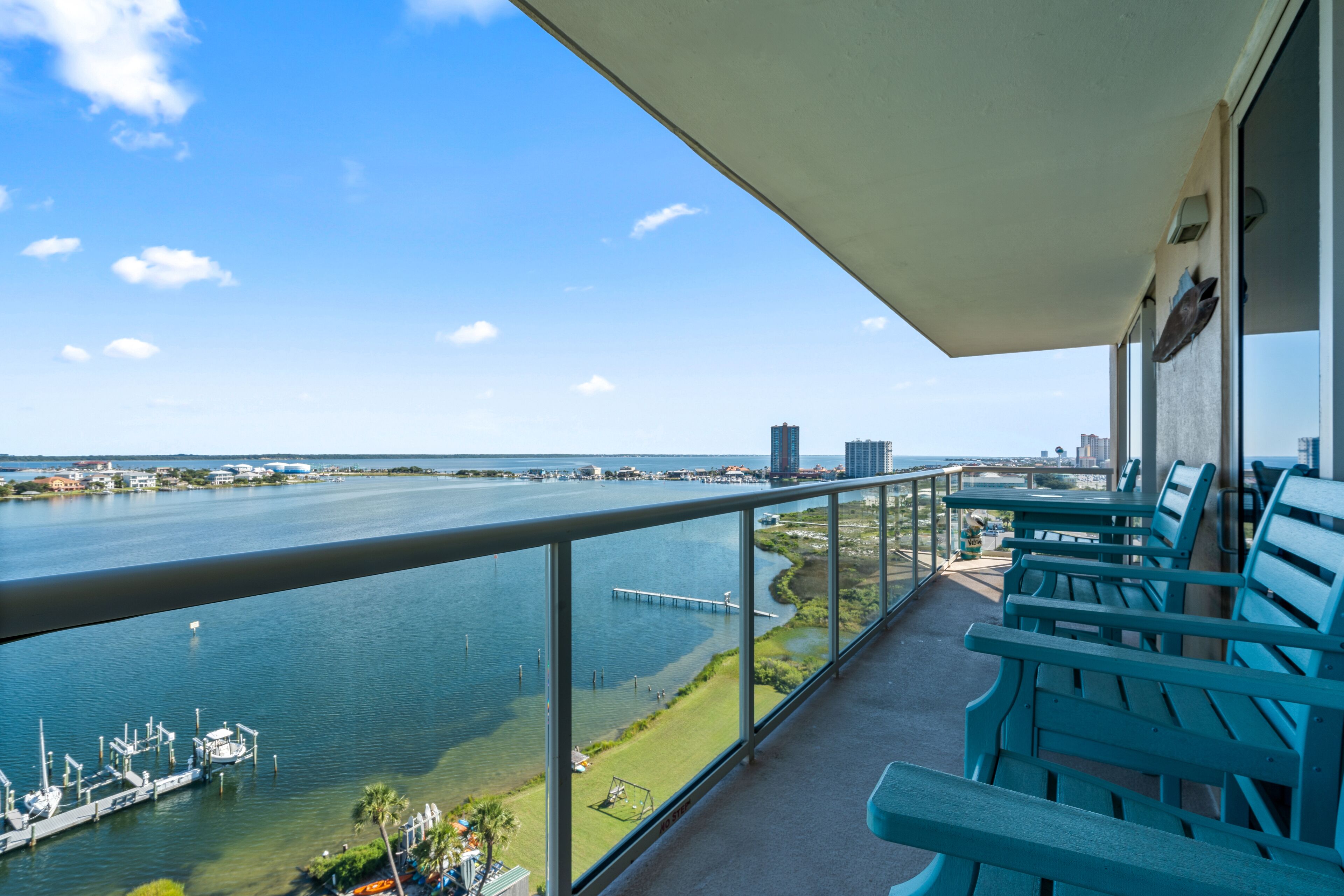 A balcony with a view of a river, boats, and distant buildings.