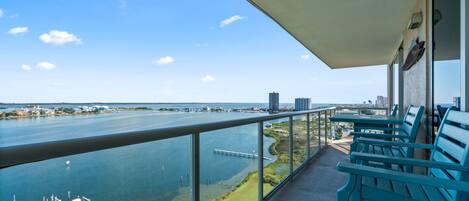 A balcony with a view of a river, boats, and distant buildings.