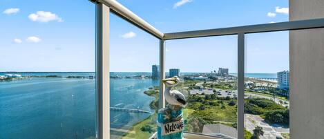 A balcony with a clear view of a waterfront, a seagull sculpture, and a 'Welcome' sign on a jar.