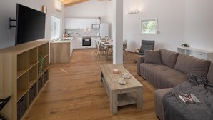 A modern living room with a wooden coffee table, a sofa, and a TV on a wooden shelf.
