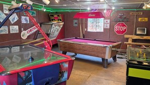Une salle de billard équipée d’une table de billard, d’une table de baby-foot et d’une table de jeu de dames.