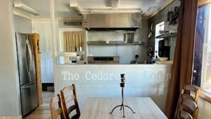 Un coin repas avec une table et des chaises, un trépied et une cuisine en arrière-plan.