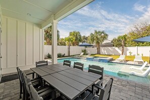 A covered patio with a pool, outdoor seating, and a view of the backyard.