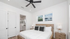 A bedroom with a bed, bedside tables, a ceiling fan, and a window with blinds.