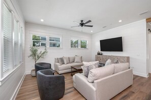 A modern living room with a sofa set, a coffee table, and a grey armchair. - New Home, Golf Cart, Walk To Beach! Private Pool! (Destin)