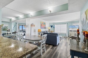 A modern living room with a dining area, a sofa, a TV, and a kitchen counter.