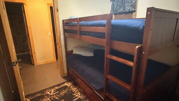 Une chambre avec un lit superposé, un ventilateur de plafond, une porte et un tapis à motifs.