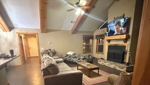 Ein gemütliches Wohnzimmer mit Kamin, Fernseher und Essbereich.