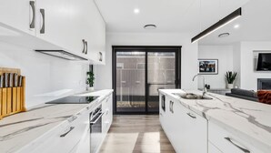 Una cocina moderna con armarios blancos, una isla central y un horno empotrado.