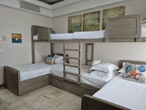 Une chambre avec un lit superposé, une petite échelle, un petit bureau et un tableau accroché au mur.