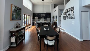 A spacious kitchen with dark cabinets, a central island, and a dining area with a long table and chairs. - Soaring ceilings, city views and private rooftop deck! (Chicago)