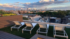 A rooftop terrace with lounge chairs and a city skyline view. - Soaring ceilings, city views and private rooftop deck! (Chicago)