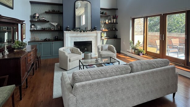 A spacious living room with a fireplace, a large sofa, and a dining area with a wooden table. - Soaring ceilings, city views and private rooftop deck! (Chicago)