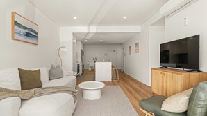 Ein modernes Wohnzimmer mit einer Couch, einem Couchtisch und einem Fernseher auf einer Holzkommode.