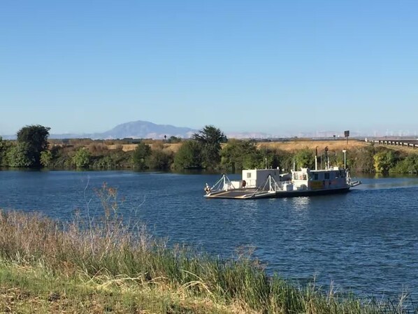 A river with a boat docked on the shore. - Eclectic Cabin + Glamping Tent at Vineyard Retreat on Grand Island in Delta (Walnut Grove)