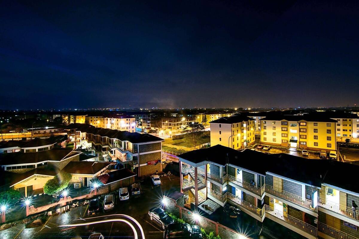 Ein mehrstöckiges Hotel mit Parkplatz und Blick auf die nächtliche Skyline der Stadt.
