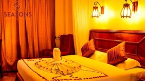 Habitación de hotel con una cama grande, cabecera de madera, lámpara de pared y cortina.
