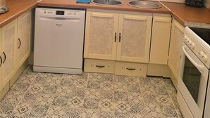 A compact kitchen with a dishwasher, double sink, and a stove. - 4-bedroom apartment in Karlovy vary (Karlovarský kraj)